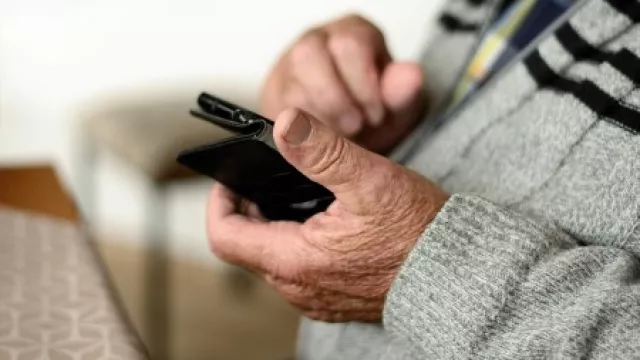 Hände eine alten Mannes bedienen ein Smartphone