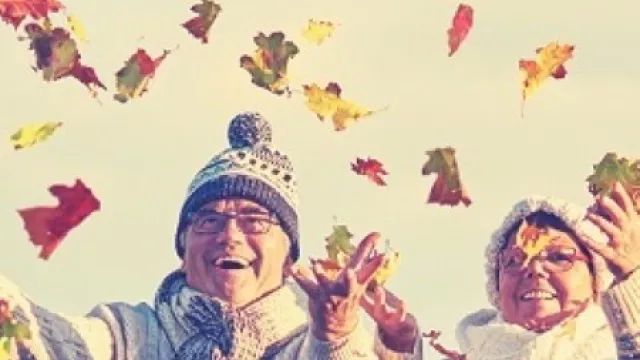 Senioren, die Blätter in die Luft werfen