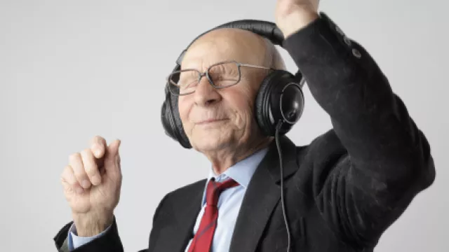 alter Mann mit Brille, Anzug und Kopfhörer tanzt zu Musik