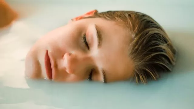 Frau liegt mit geschlossenen Augen entspannt in der Badewanne