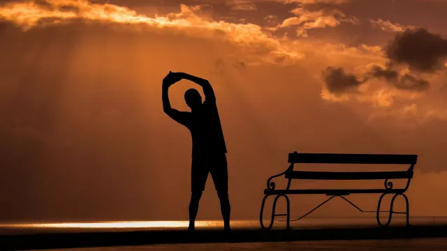 Mann bewegt sich neben Parkbank im Sonnenuntergang