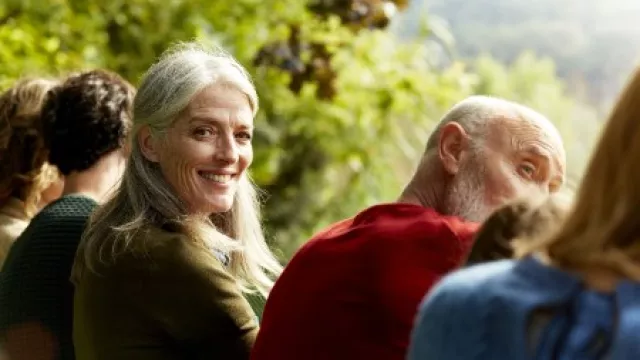 weißhaarige ältere Frau sitzt in dein Gruppe von verschieden alten Menschen