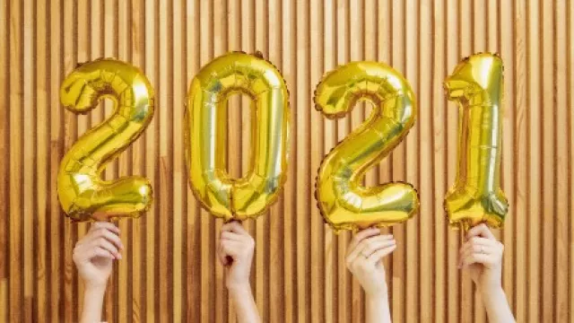 4 goldene Luftballons mit den Ziffern 2021 werden von 4 Händen hochgehalten