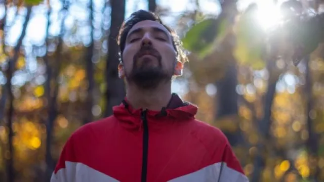 Mann der bewusst atmet im Wald mit untergehender Sonne im Herbst
