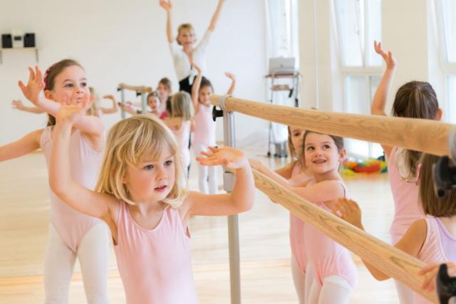 Foto von kleinen Mädchen die eine Ballettgeste am Balken machen