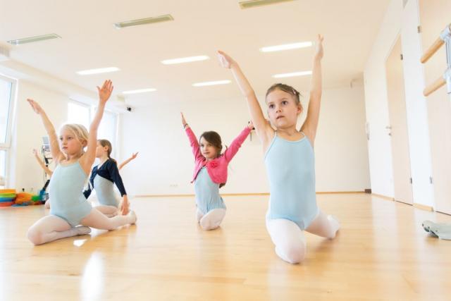 Foto von Kindern beim Ballettunterricht im Spagat am Boden
